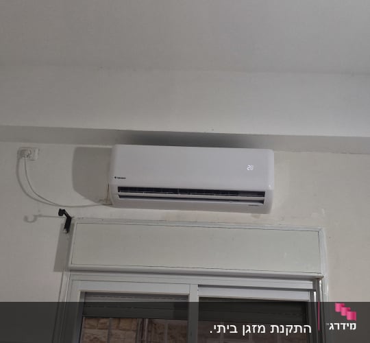 התקנת מזגן עילי לבן מעל חלון בבית